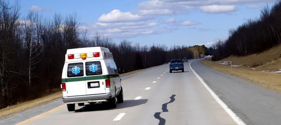 An ambulance drives down a rural road.